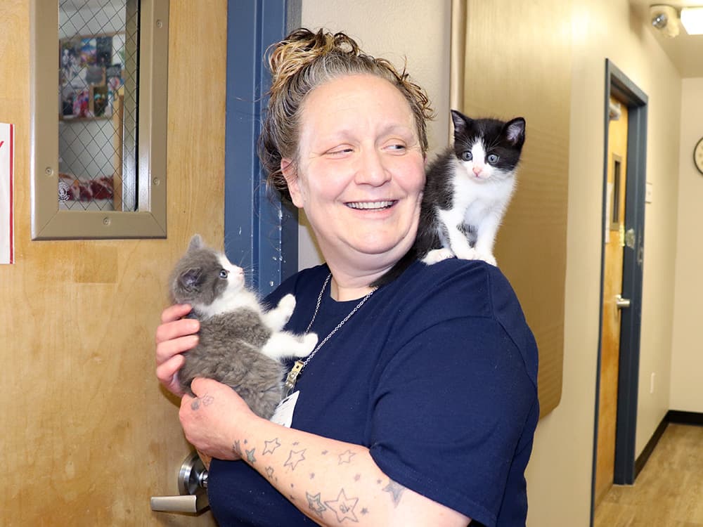 woman holding two foster kittens