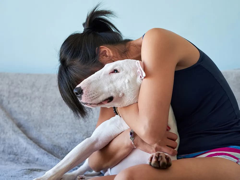 woman hugging sad dog